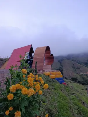 a building on the side of a hill with flowers at Glamping arcoiris r in Ciudad Bolívar