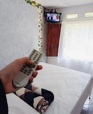 a person holding a remote control next to a bed at Apartamento en concepción entorno natural in Concepción