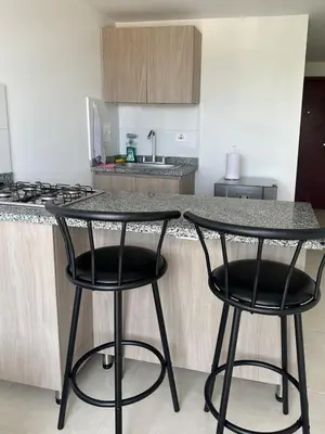 a kitchen with two black bar stools at a counter at Lindo Apto central Urban Mzles in Manizales