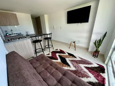 a living room with a couch and a kitchen at Lindo Apto central Urban Mzles in Manizales