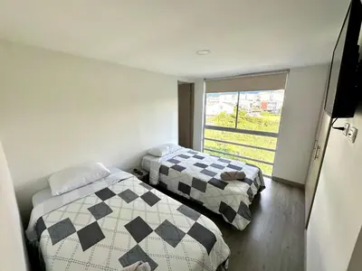 two beds in a small room with a window at Lindo Apto central Urban Mzles in Manizales