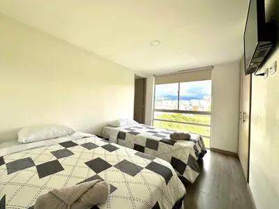 two beds in a room with a large window at Lindo Apto central Urban Mzles in Manizales