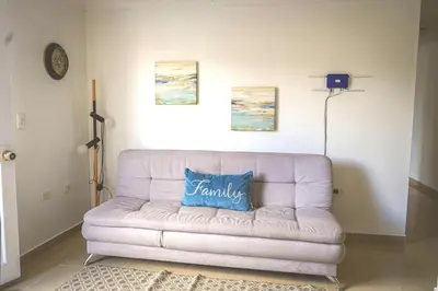 a white couch in a living room with a blue pillow at Comodo apartamento 2-2 - Parqueo cubierto para 1 carro - En el corazón de Guatape in Guatapé