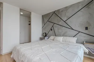 a white bed in a bedroom with a large wall at 15minPOBLADO-LUXURY-Sabaneta in Sabaneta