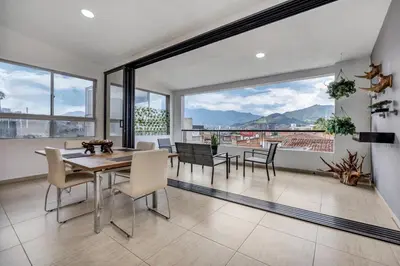 a dining room with a table and chairs and large windows at Luxury Penthouse Con Aire acondicionado in Envigado