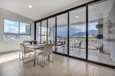 a dining room with a table and chairs and large windows at Luxury Penthouse Con Aire acondicionado in Envigado