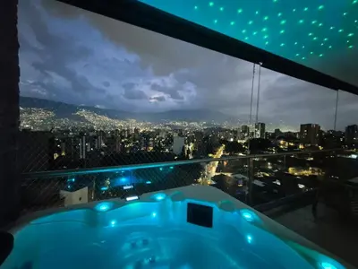 a bath tub with a view of the city at night at Laureles 11th Floor, Jacuzzi and AC in Medellín