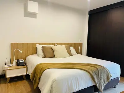 a bedroom with a large bed with a wooden headboard at Suite Rioverde Hotel Rionegro in Rionegro