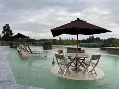 a table and chairs with an umbrella on top of water at Suite Rioverde Hotel Rionegro in Rionegro