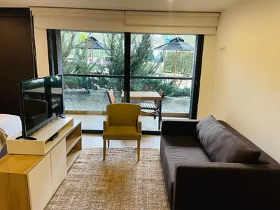 a living room with a couch and a television at Suite Rioverde Hotel Rionegro in Rionegro