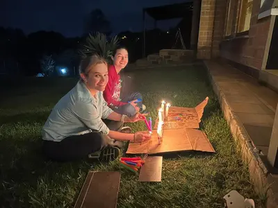two women sitting in the grass with a birthday cake with candles at Ohana in Medellín
