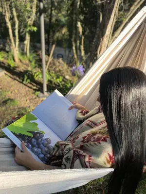 a girl laying on a hammock reading a book at Cabernet Cabaña - La Cava Lodge in Medellín