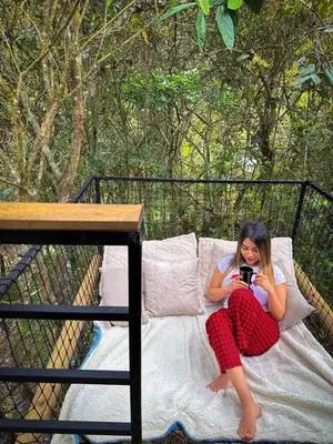 a woman sitting on a couch taking a picture with a camera at Cabaña Lambrusco - La Cava Lodge in Medellín