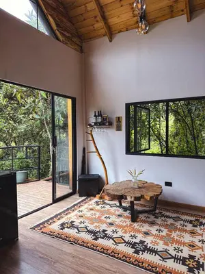 a living room with a table and a rug at Cabaña Malbec - La Cava Lodge in Medellín