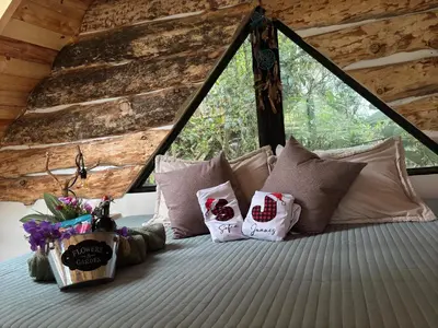 a bedroom with a bed with pillows and a window at Cabaña Malbec - La Cava Lodge in Medellín