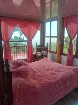 a bedroom with a bed with red blankets and windows at Perla del Ruiz in Manizales