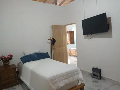 a bedroom with a bed and a flat screen tv at finca nalu in Jardin