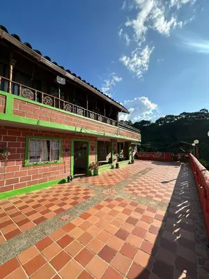 a building with a brick courtyard with a balcony at ENTRE LOMAS GLAMPING - Finca el Reposo in Girardota
