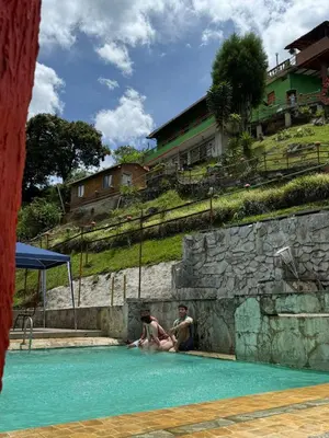 two people sitting in the water in a swimming pool at ENTRE LOMAS GLAMPING - Finca el Reposo in Girardota