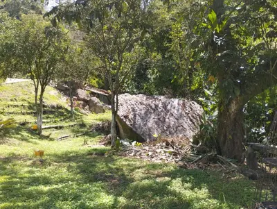 a large rock in the middle of a field with trees at ENTRE LOMAS GLAMPING - Finca el Reposo in Girardota