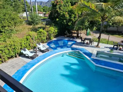 a blue swimming pool with chairs and tables at cabaña in Honda