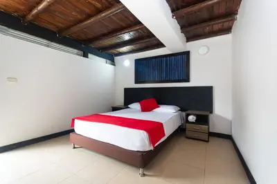 a bedroom with a large bed with a red blanket at Finca Hotel Santo Tomas Campestre in Rionegro