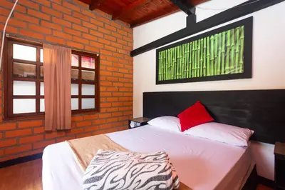 a bedroom with a white bed with red pillows at Finca Hotel Santo Tomas Campestre in Rionegro