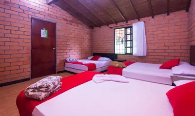 a room with three beds and a brick wall at Finca Hotel Santo Tomas Campestre in Rionegro