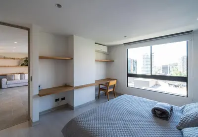 a bedroom with a bed and a desk and a window at The best location in Poblado Air conditioning in Medellín
