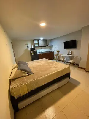a bedroom with a large bed and a kitchen at Apartaestudio 304 in Medellín
