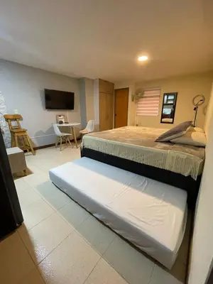 a bedroom with two beds and a living room at Apartaestudio 304 in Medellín