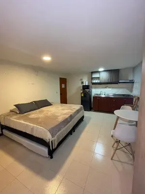a large bedroom with a bed and a kitchen at Apartaestudio 304 in Medellín