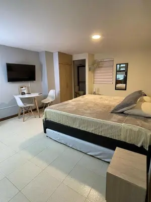 a bedroom with a bed and a table and a television at Apartaestudio 304 in Medellín