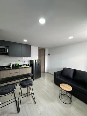 a living room with a black couch and a kitchen at céntrico y acogedor apartamento in Sabaneta