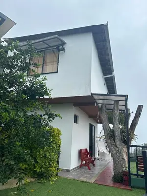 a white house with a red chair and a tree at Casa Campestre in Santa Bárbara