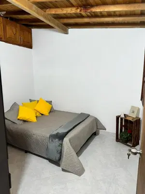 a bed with yellow pillows in a white room at Pedacito de cielo in Jardin