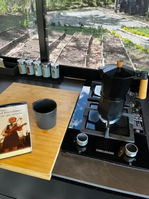 a coffee pot on a stove next to a book at Tiny House Minimalista en la Naturaleza cerca a El Retiro y La Ceja in El Retiro