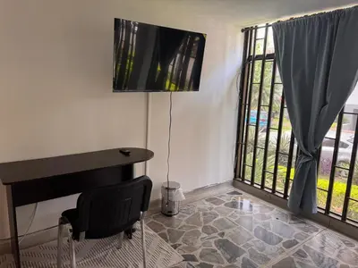 a room with a piano and a desk and a window at Nice place to stay in Medellín