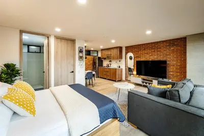 a bedroom with a large bed and a living room at Apartamentos Medellín Caribe Suite in Medellín