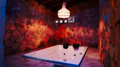 a bath tub in a room with a stone wall at Oru Forest Retreat & Eco Lodge, just 15 minutes from the airport in Envigado