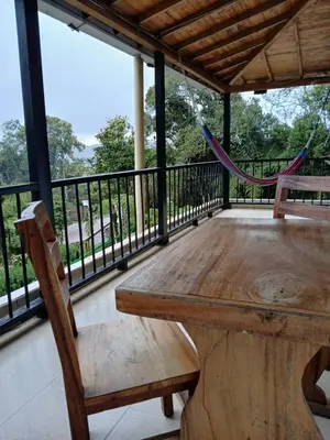 a wooden table and chairs on a porch with a hammock at Oru Forest Retreat & Eco Lodge, just 15 minutes from the airport in Envigado