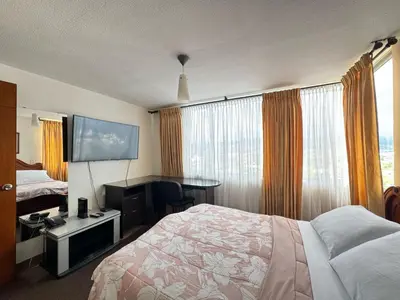 a hotel room with a bed and a flat screen tv at Cantabria in Manizales