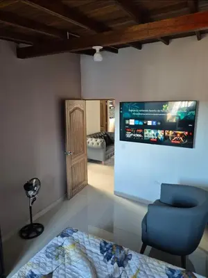 a room with a blue chair and a tv on the wall at Apartamento Super Lindo in Medellín