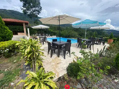 a patio with tables and umbrellas next to a pool at Finca Villa Andrea 1h20min desde Medellín Niquía in Santa Rosa de Osos