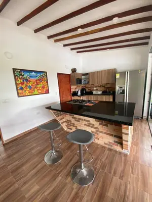 a kitchen with a black counter and two bar stools at Finca Villa Andrea 1h20min desde Medellín Niquía in Santa Rosa de Osos