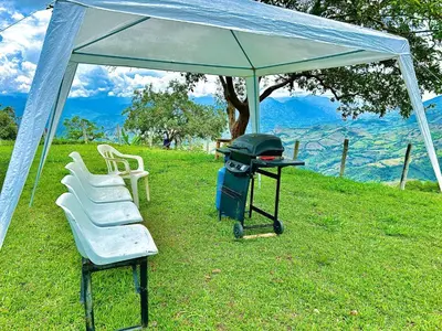 a tent with a grill and chairs in the grass at Almalu Finca in Filadelfia