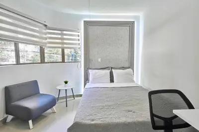 a bedroom with a bed and a chair and a window at El Poblado 4 Bedrooms 2 Baths Private Terrace in Medellín