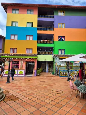 a colorful building with tables and chairs in front of it at Apartamento central en Guatape - 2 habitaciones - 2 baños - Ideal familias in Guatapé