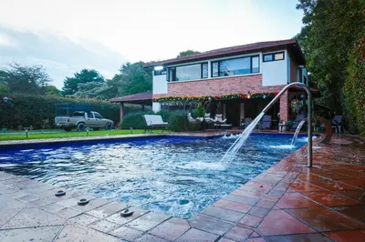 a pool with a fountain in front of a house at VILLA DOLLS PRIVADA CON SAUNA, PISCINA Y MAs in Rionegro