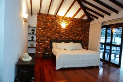 a bedroom with a bed and a brick wall at VILLA DOLLS PRIVADA CON SAUNA, PISCINA Y MAs in Rionegro